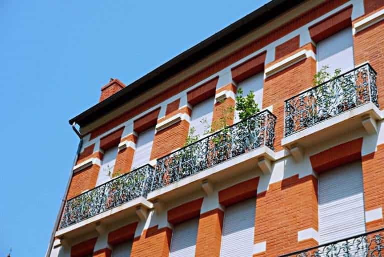 Ocre building with white blinds and balcony - Visit Occitanie
