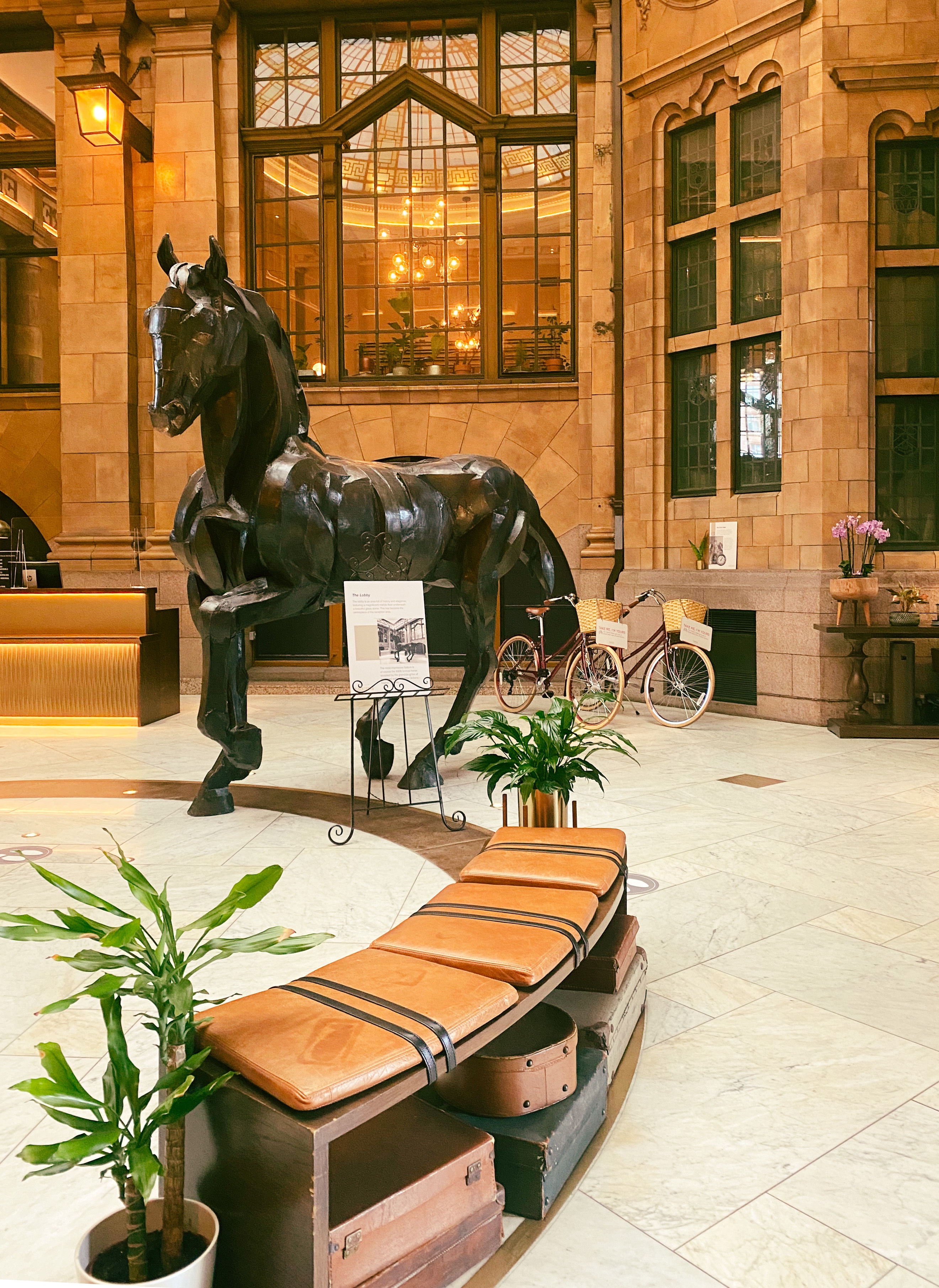 The lobby of Kimpton Clocktower Hotel with a black horse and two vintage bikes
