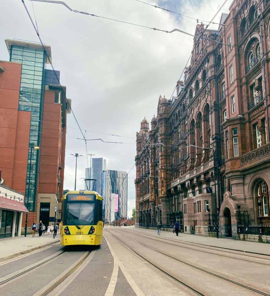 A yellow tram running between a modern and old building