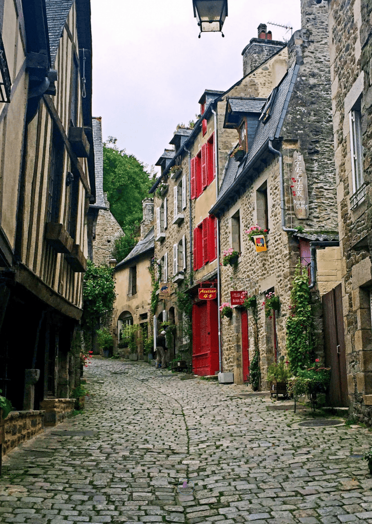 Things To Do In Brittany, France: A Journey Through Scenic Landscapes, And Authentic Culture. 14 A charming cobblestone street in Dinan lined with vibrant red and yellow buildings.