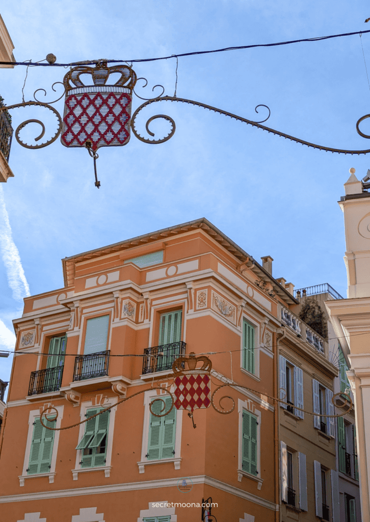 A sunny street in Monaco featuring a building adorned with a prominent sign, perfect for a day trip exploration.