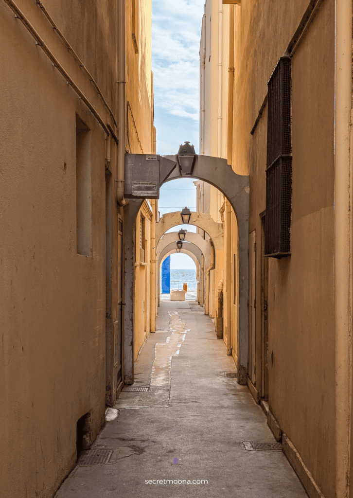 The Perfect One Day in Menton Itinerary: Discover Hidden Gems 30 A narrow alley illuminated by a warm light from an archway