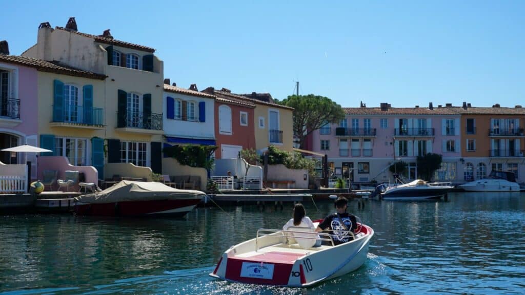 Port Grimaud: The Ultimate Guide to Provence's Little Venice 16 A small boat is traveling down a canal in front of colorful houses in Port Grimaud