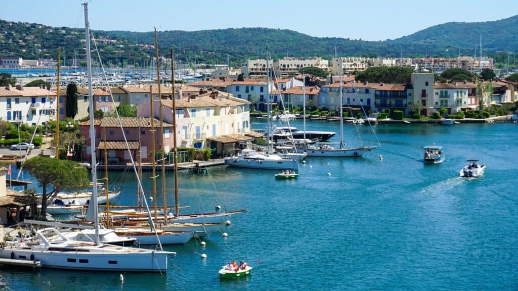 Port Grimaud: The Ultimate Guide to Provence's Little Venice 14 Boats are docked in a harbor with houses and mountains in the background in Port Grimaud