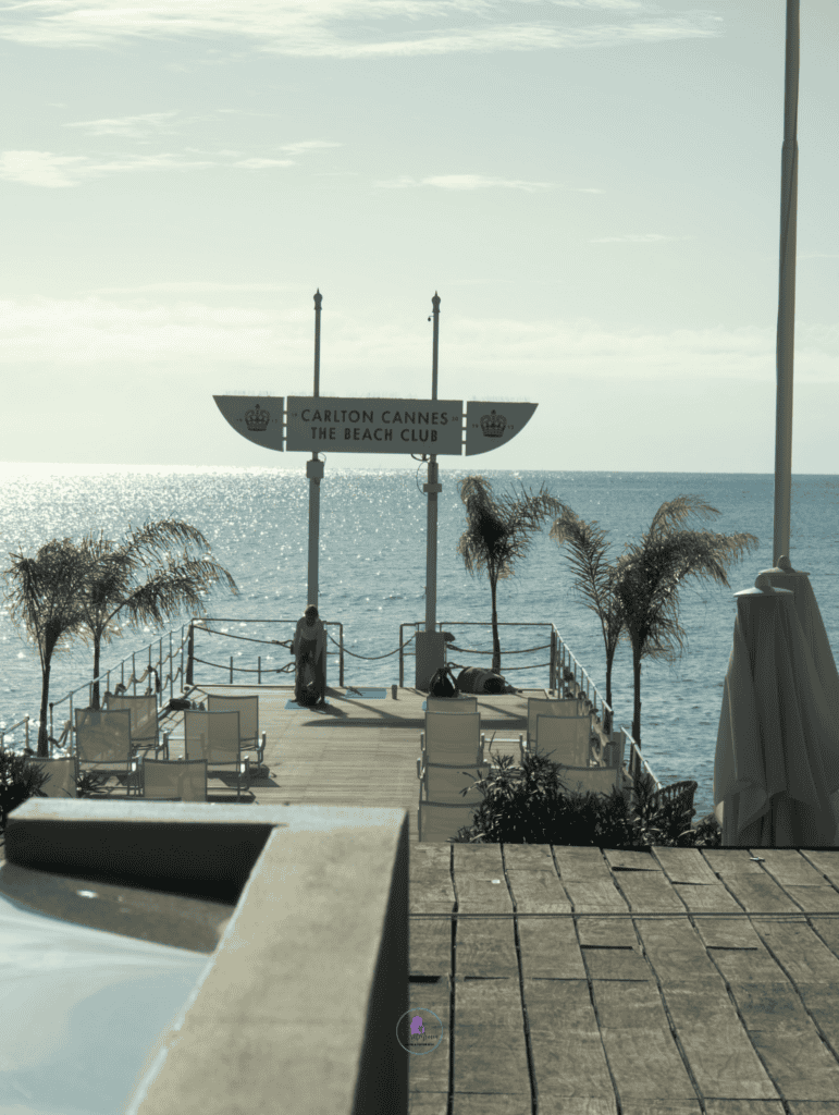 The Perfect 7-Day French Riviera Itinerary: Ultimate Côte d’Azur Travel Guide 34 Carlton Cannes Beach Club pier with palm trees, sun loungers and Mediterranean Sea views.