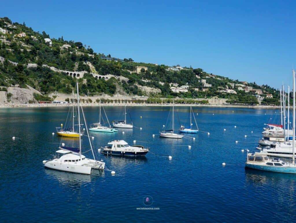 The Perfect 7-Day French Riviera Itinerary: Ultimate Côte d’Azur Travel Guide 14 Boats anchored in a serene French Riviera harbor with lush hillside views in the background.
