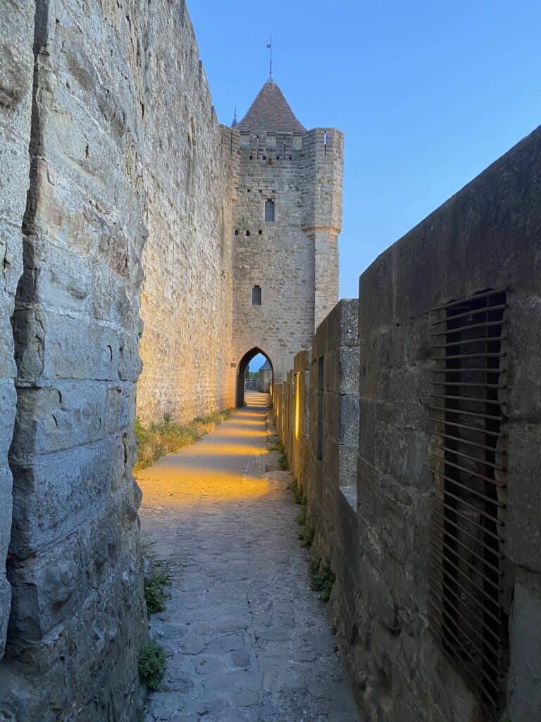 Beautiful Medieval Towns in France for History Lovers 16 Cobblestone path beside the towers and defensive walls of the medieval citadel of Carcassonne