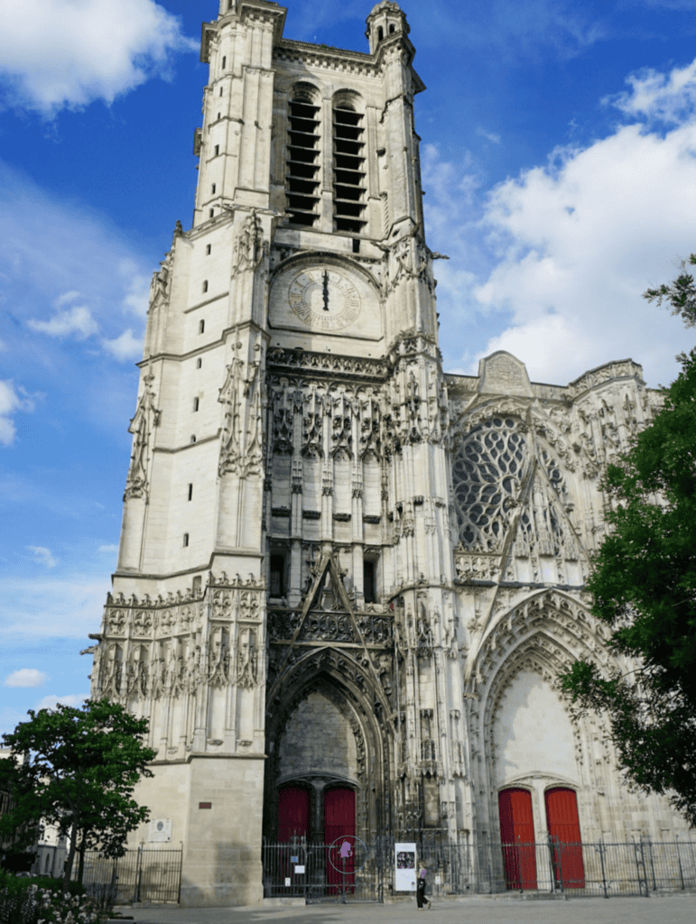 Gothic facade and clock tower of Troyes Cathedral under a blue sky
