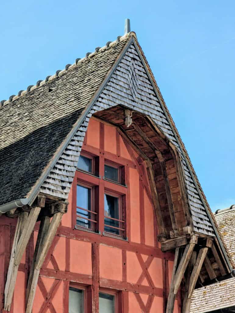 Beautiful Medieval Towns in France for History Lovers 2 Close-up of a red half-timbered medieval house with wooden roof details in Troyes