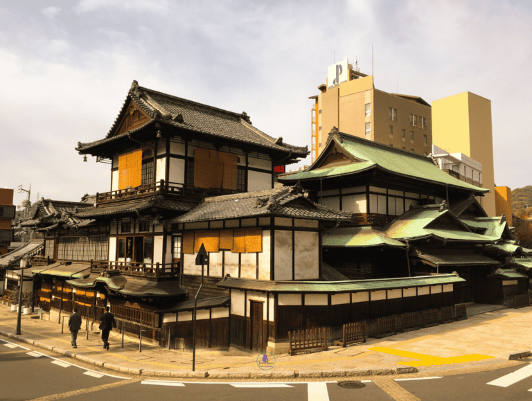 The historic wooden Dogo Onsen Honkan bathhouse with tiered roofs and green copper eaves in Matsuyama, Ehime