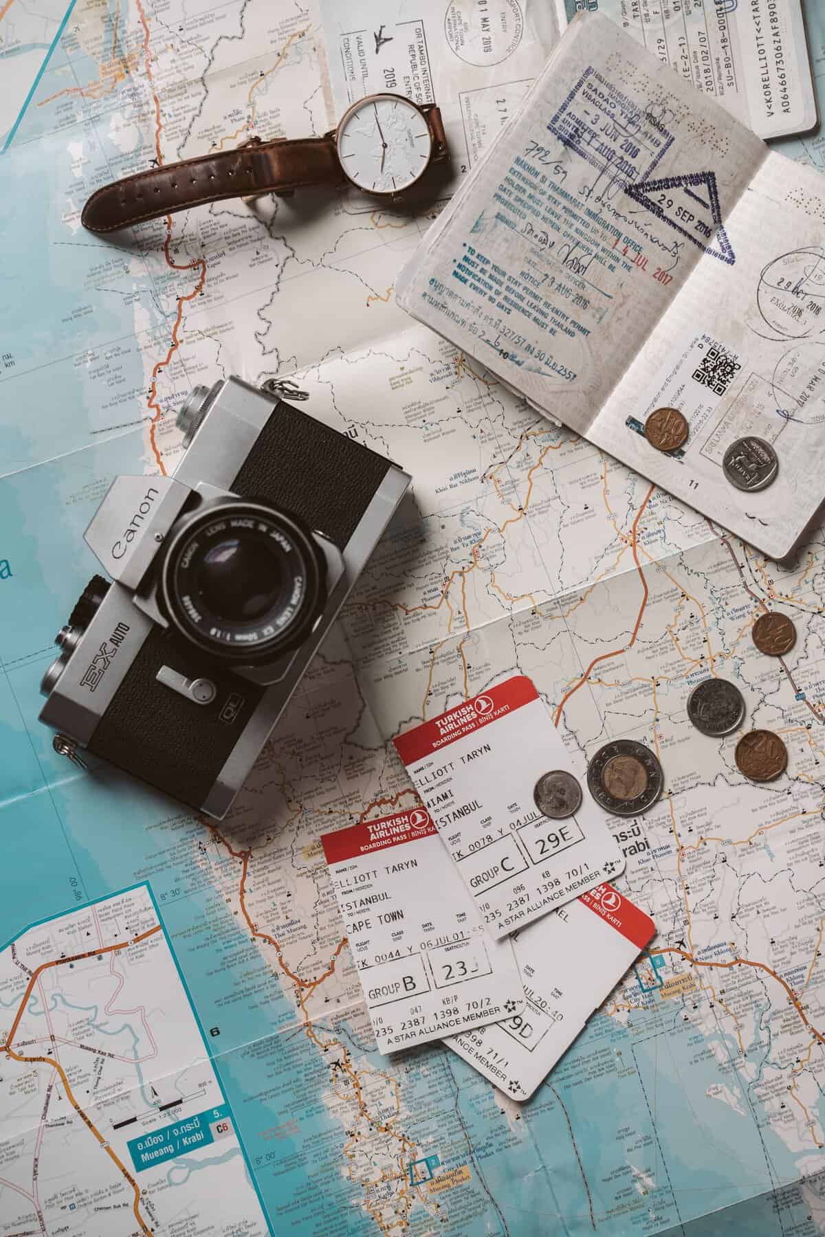 My Favourite Travel Resources. Flat lay travel essentials including passports, tickets, and a vintage camera on a world map.