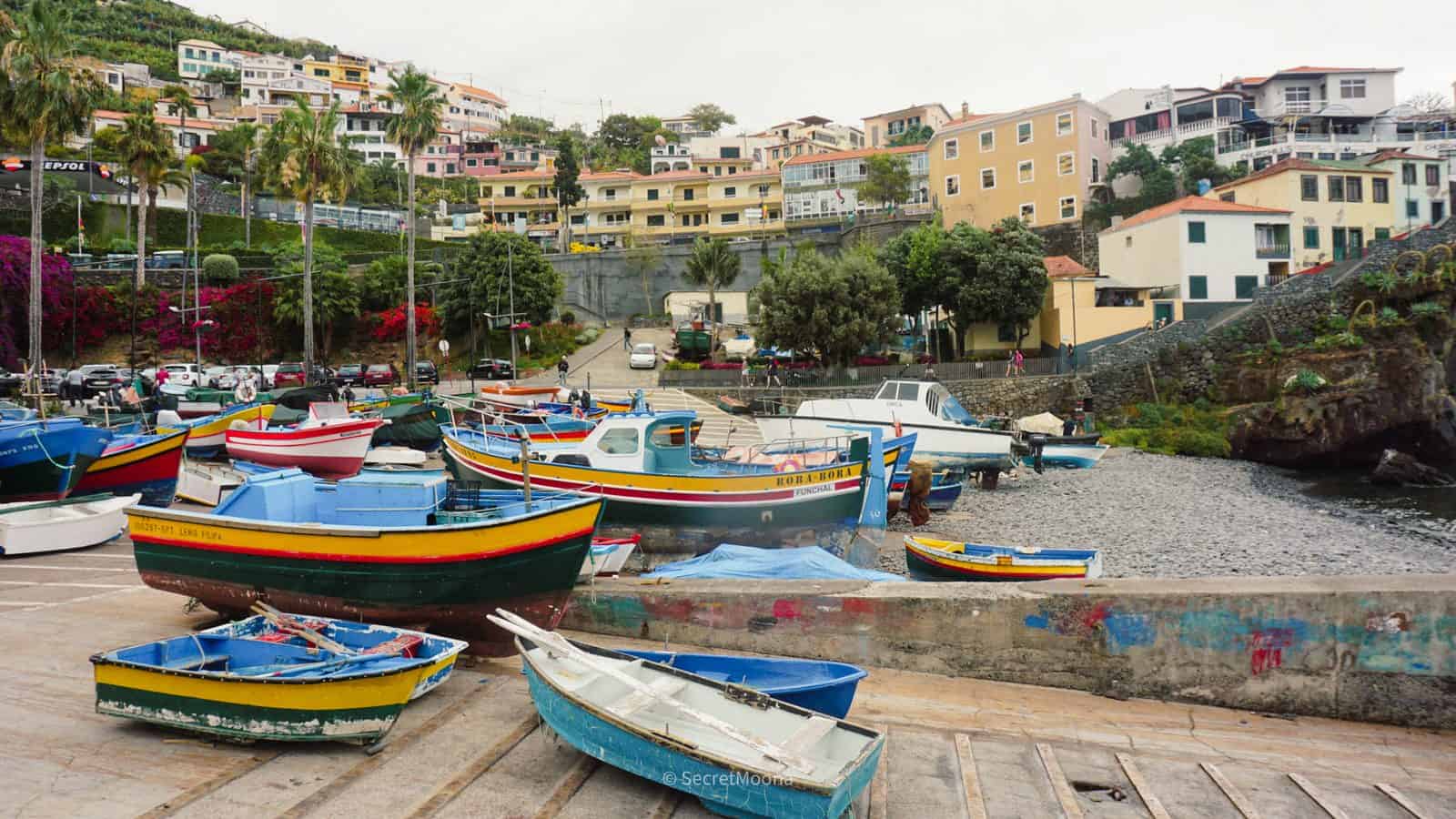 Painted wooden fishing boats pulled up on the shore at Câmara de Lobos harbour