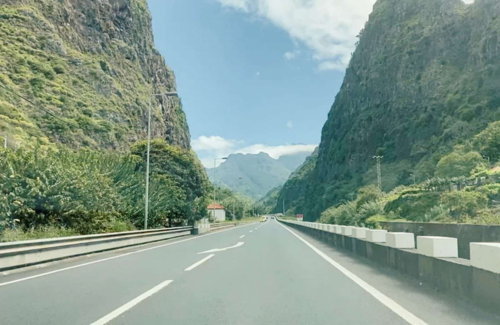 A wide mountain road curving between steep green cliffs on Madeira
