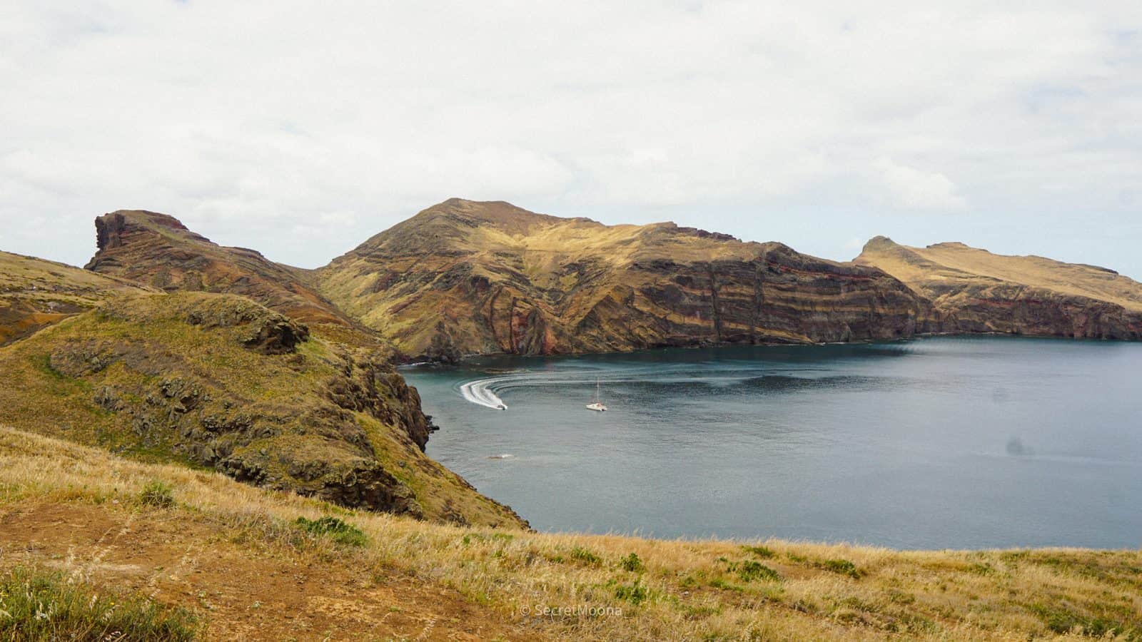 Ochre volcanic ridges and a curved blue bay along the Ponta de São Lourenço peninsula