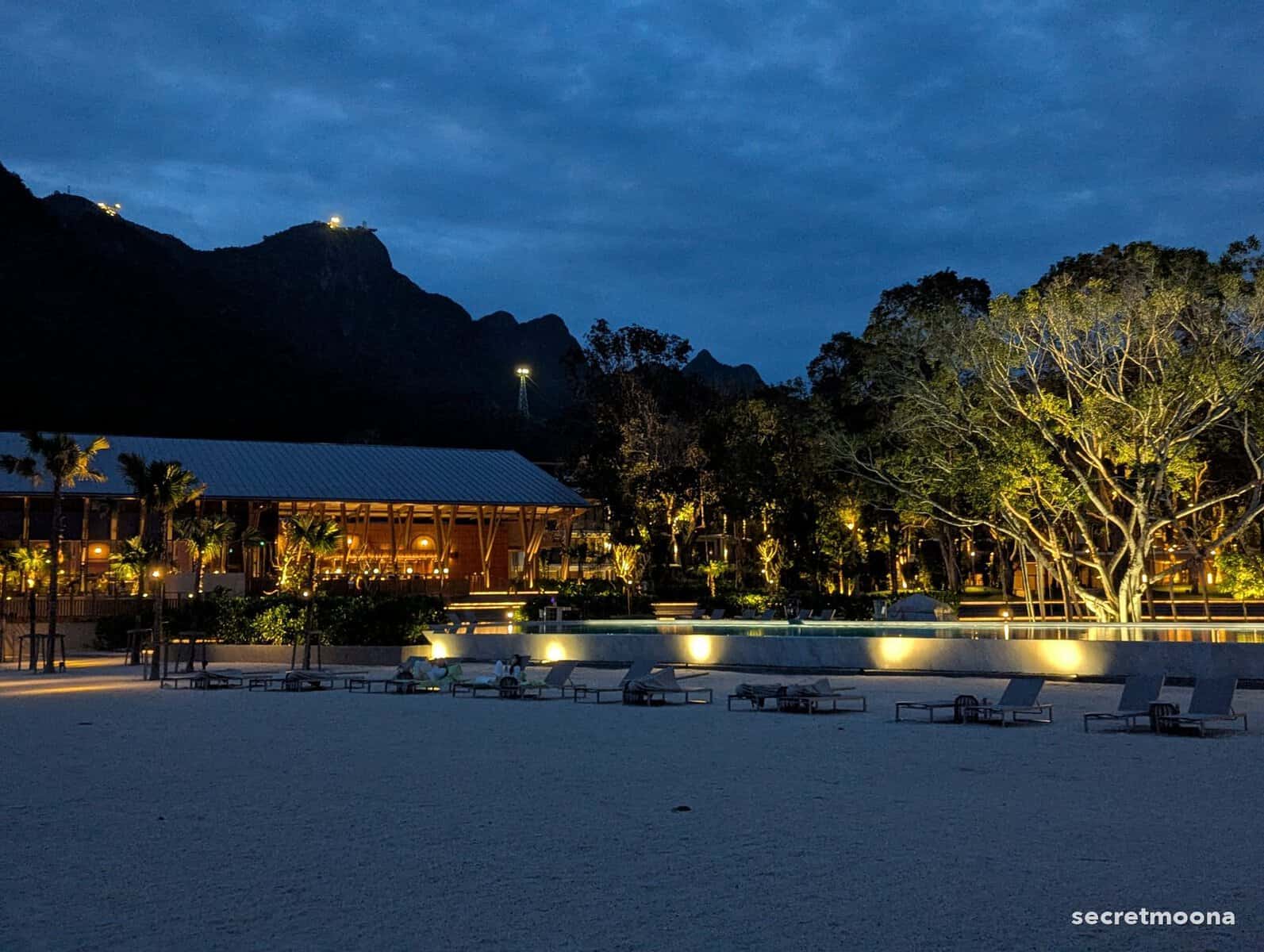 Hilton Burau Bay Langkawi Resort lit up at dusk, seen from the beach