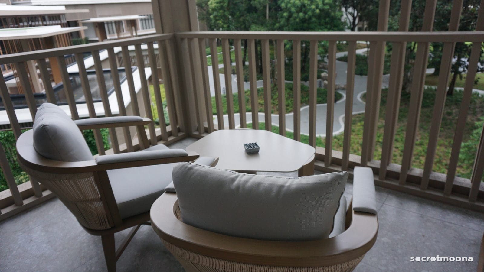 Two timber-framed armchairs on a private balcony looking into rainforest at Hilton Burau Bay Langkawi