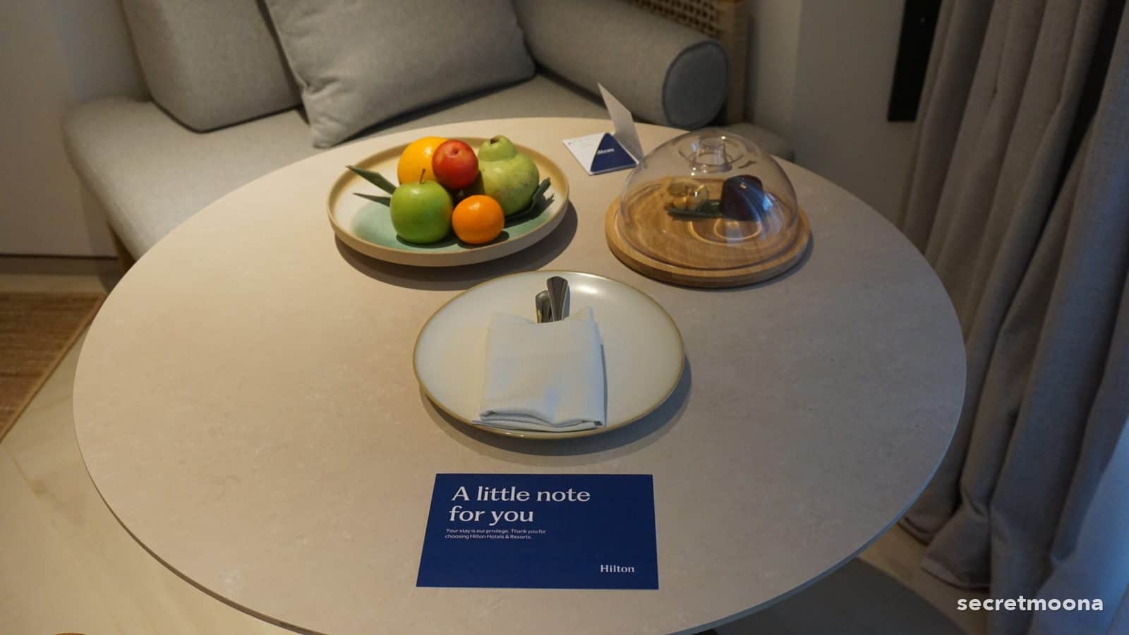 A built-in banquette and round stone table in the seating corner of a room at Hilton Burau Bay Langkawi