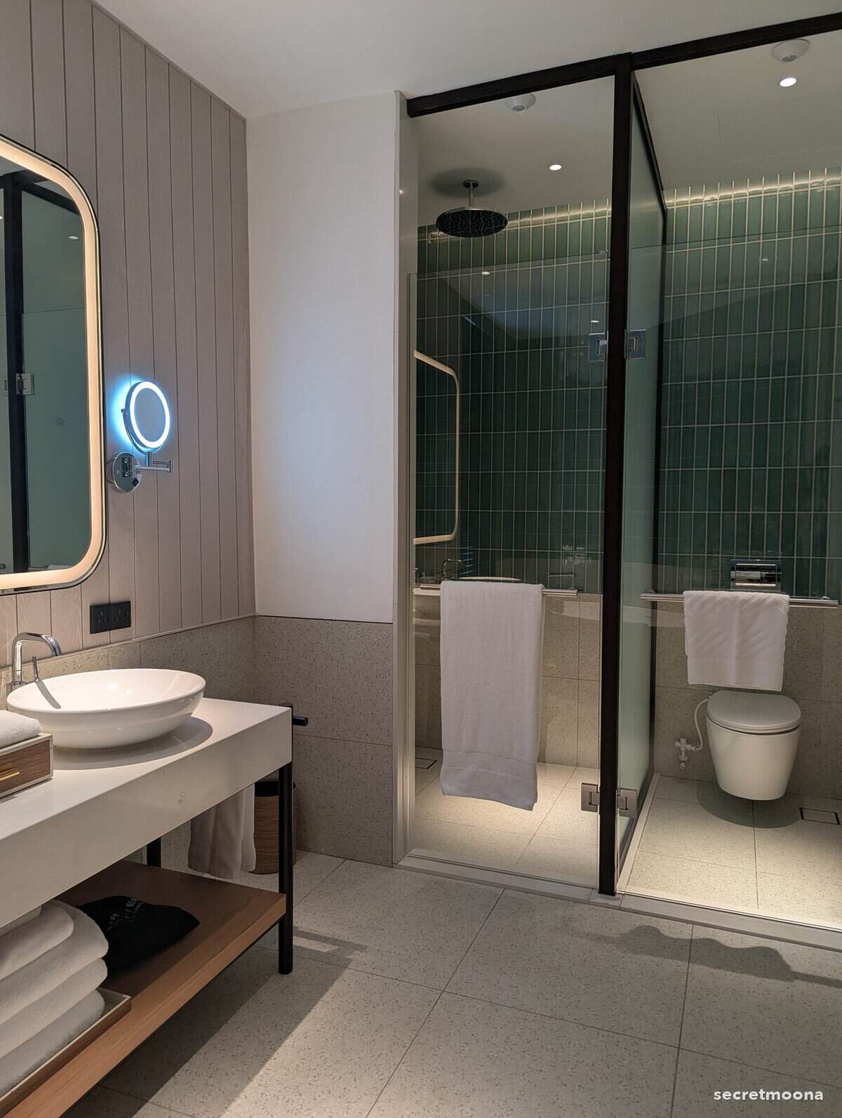 A glazed walk-in shower lined in deep green tile beside a separate lavatory compartment