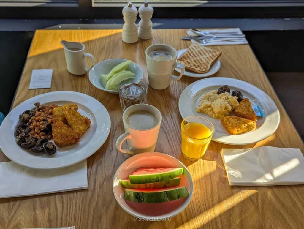 A full breakfast table with eggs, hash browns, fruit, juice and coffee