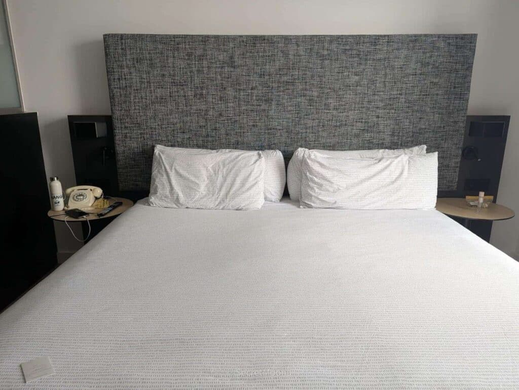 King bed with white linen and a grey headboard at INNSiDE Liverpool