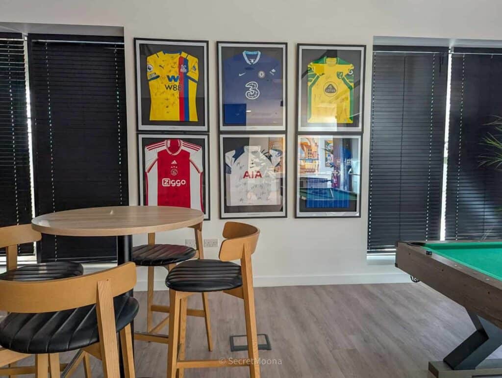 Recreation space with a pool table, bar stools and framed football shirts