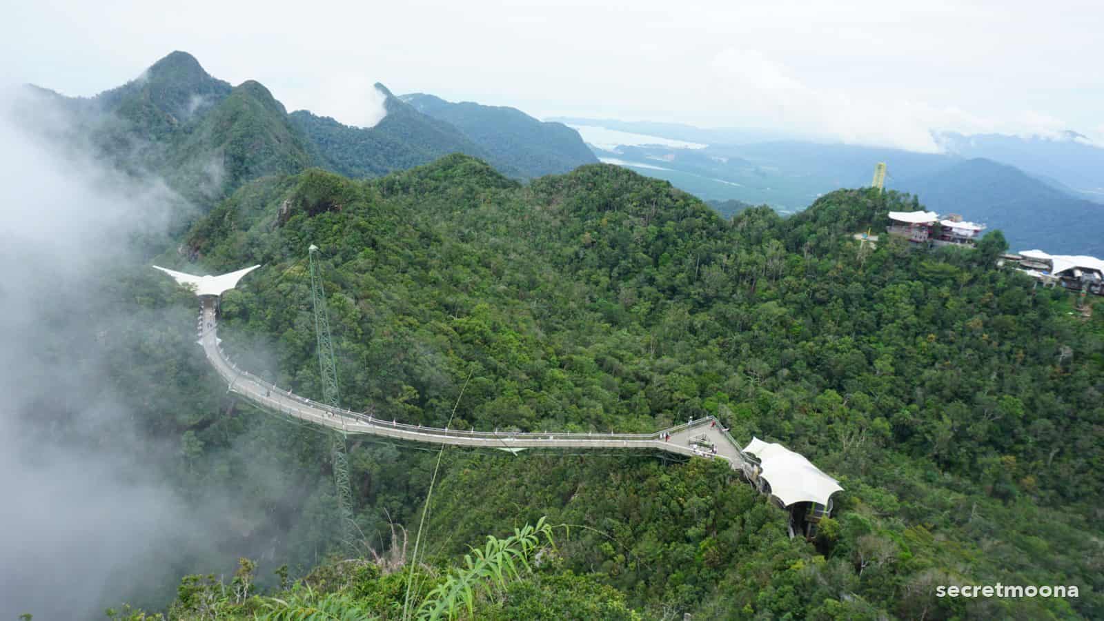 The curved Langkawi Sky Bridge emerging from cloud above the rainforest